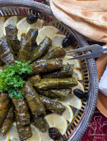 Armenian Sarma on a silver platter garnished with lemon wedges and black olives