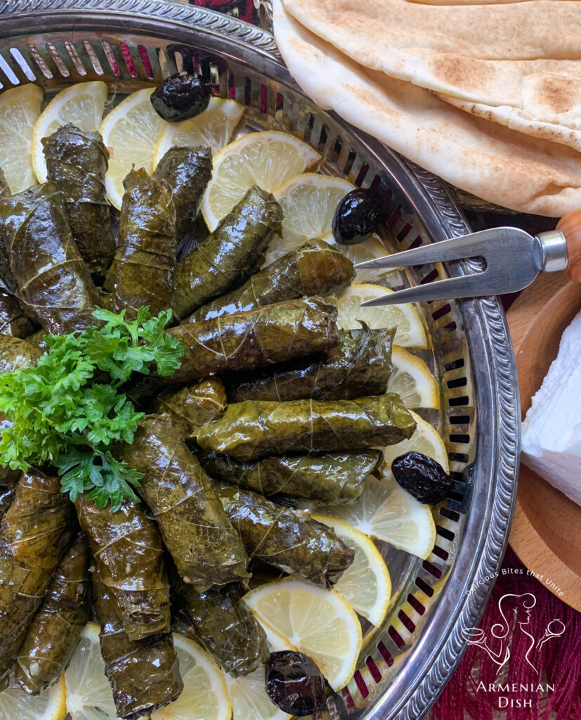 Stuffed grape leaves on table next to pita bread and feta cheese